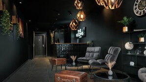 A modern lounge area with leather armchairs, a wooden coffee table, and a leather ottoman. - THE ROOMS - Hotel & House (Frankfurt)