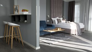 A modern bedroom with a bed, a desk, and a blue sofa. - THE ROOMS - Hotel & House (Frankfurt)