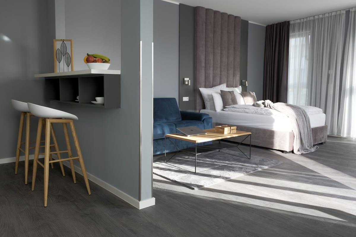 A modern bedroom with a bed, a desk, and a blue sofa.