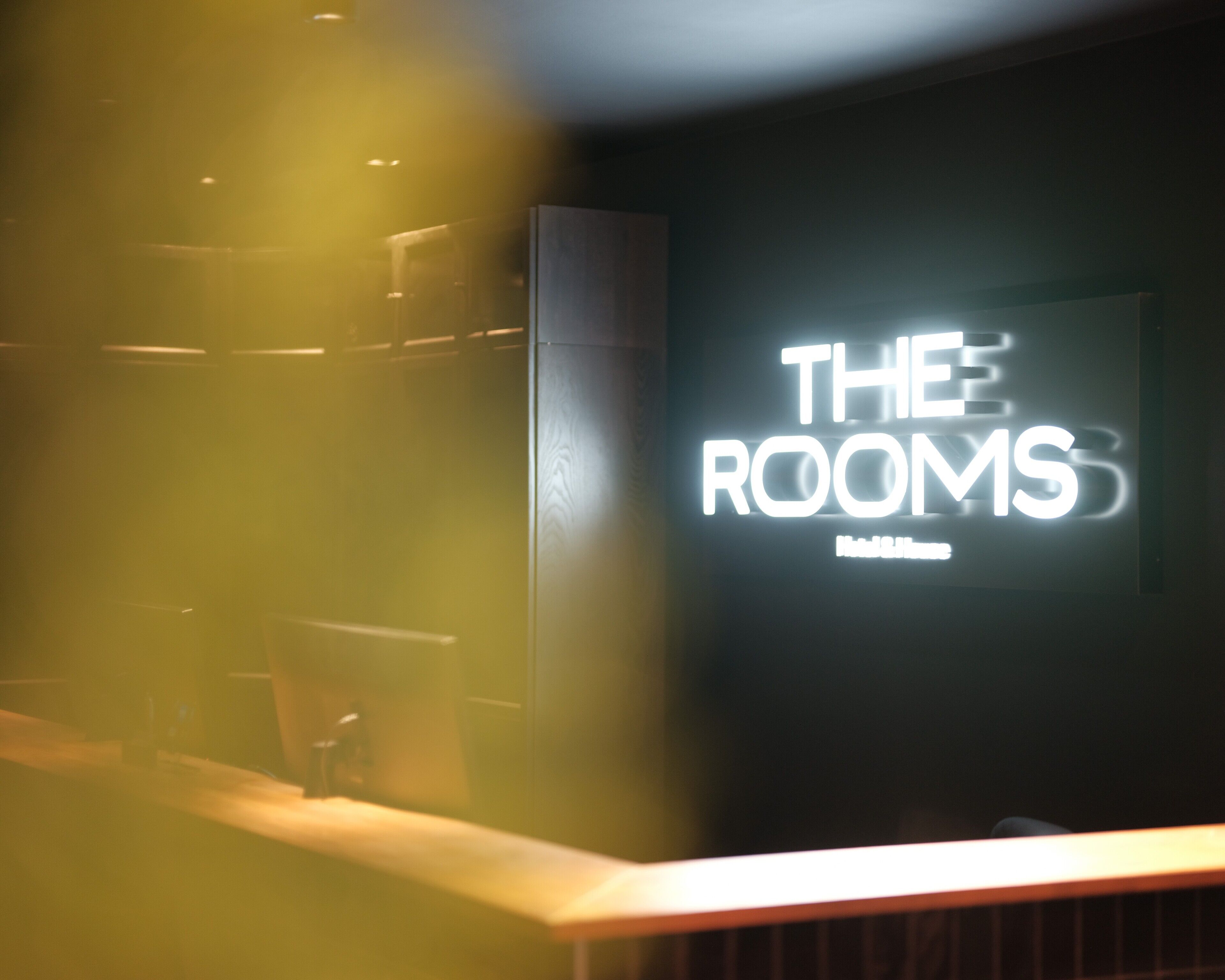 A hotel sign with the text "THE ROOMS" and "Hotel & Suites".