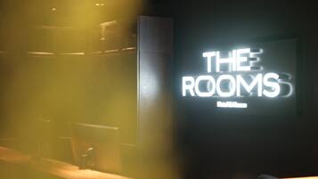 A hotel sign with the text "THE ROOMS" and "Hotel & Suites".