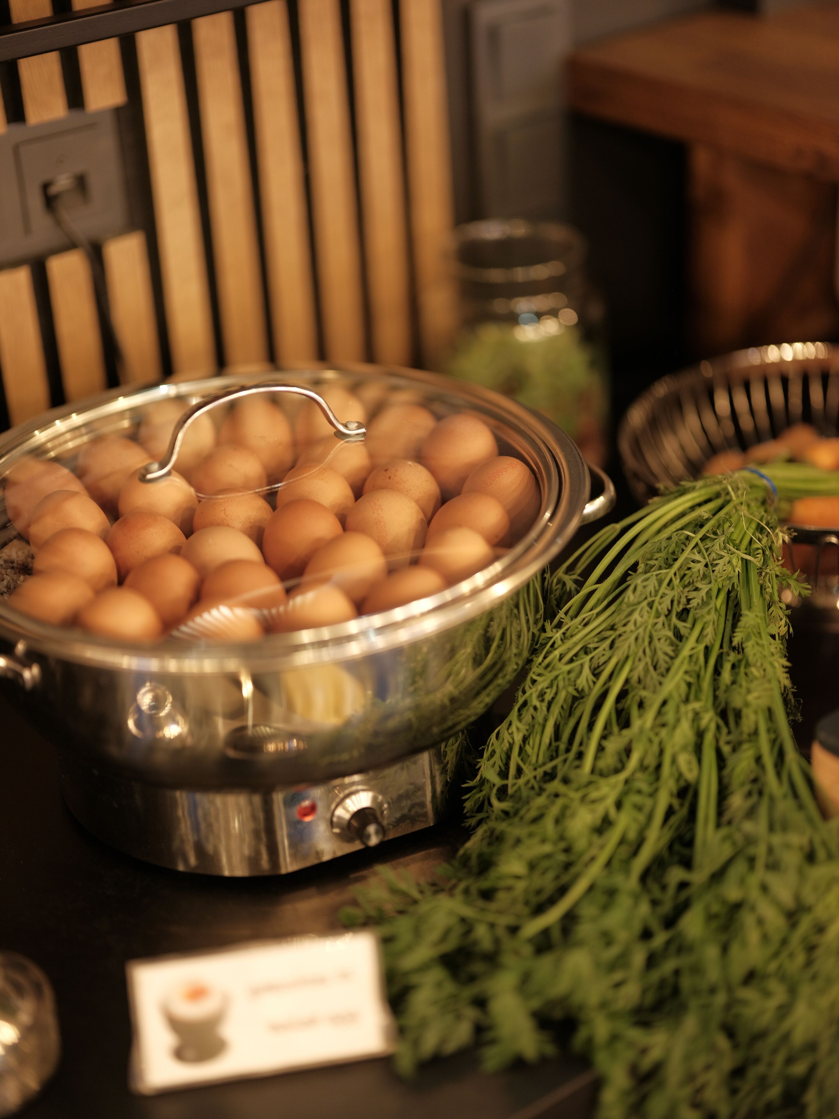 A buffet setup with a pot of eggs and a bunch of green vegetables.