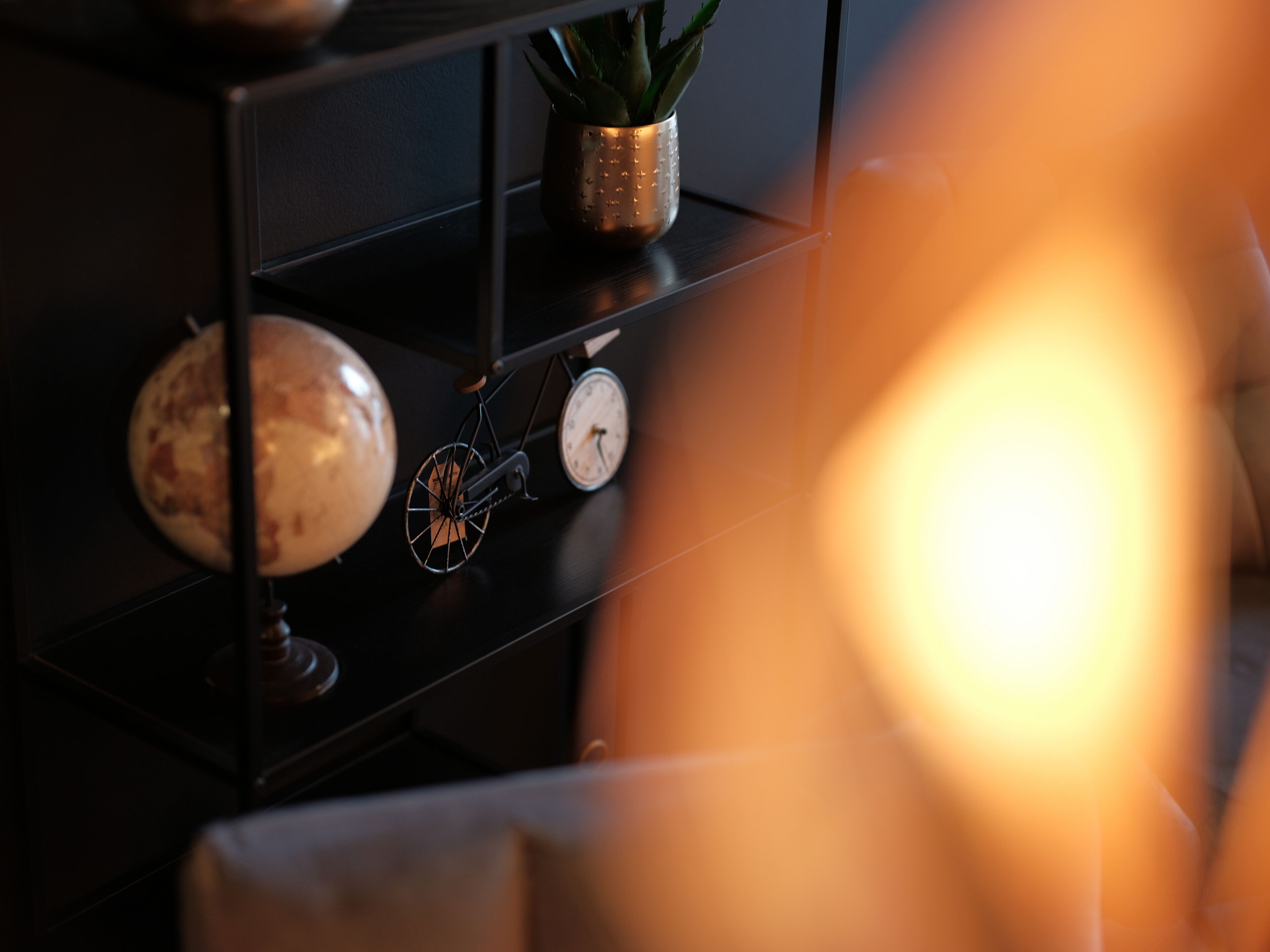 A shelf with a globe, a clock, and a potted plant.