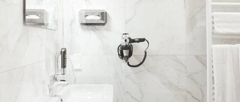 A bathroom with a white sink, a handheld showerhead, and a towel rack.