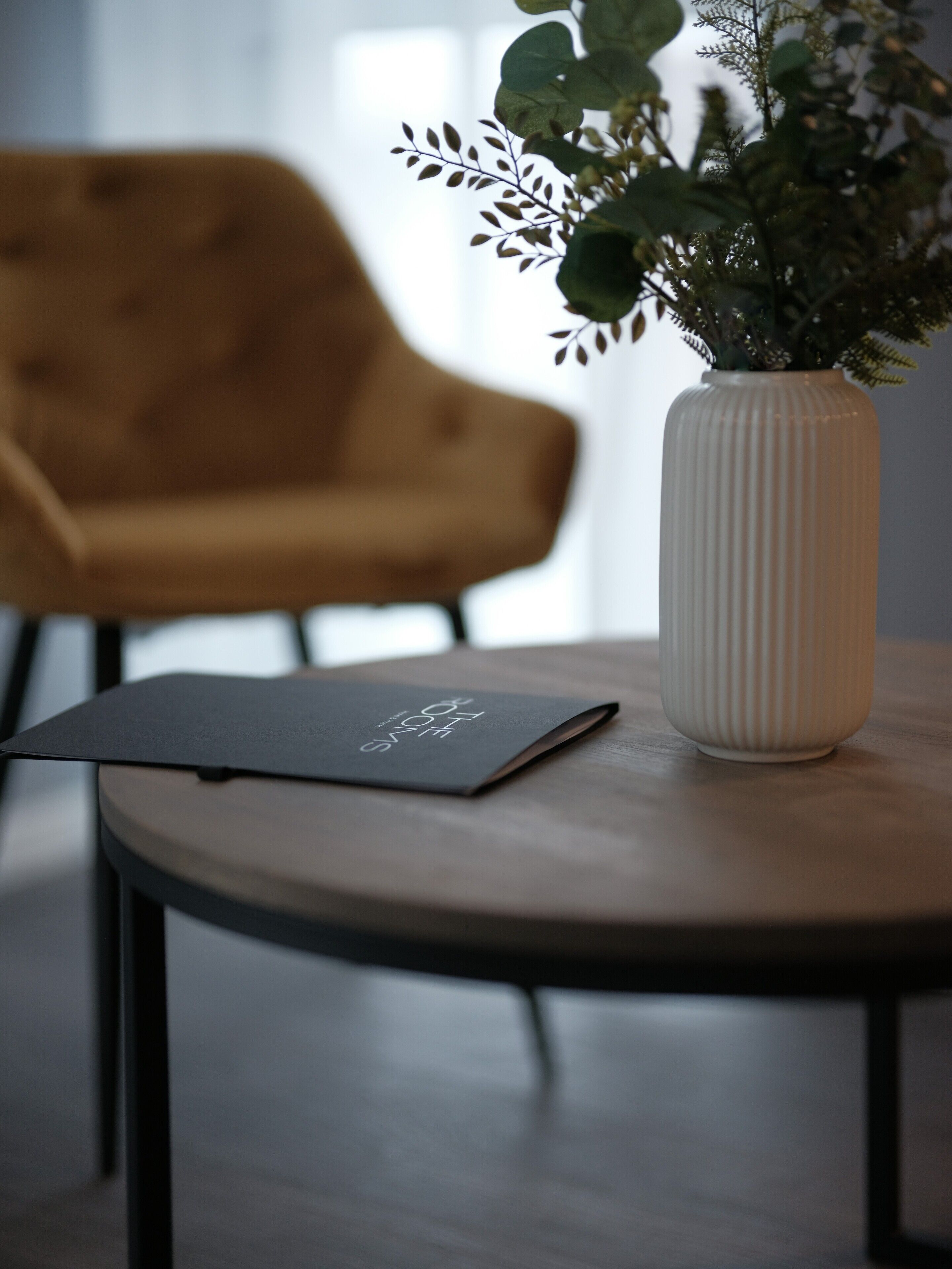 Une pièce moderne avec une table ronde en bois, une plante en pot et un dossier noir.