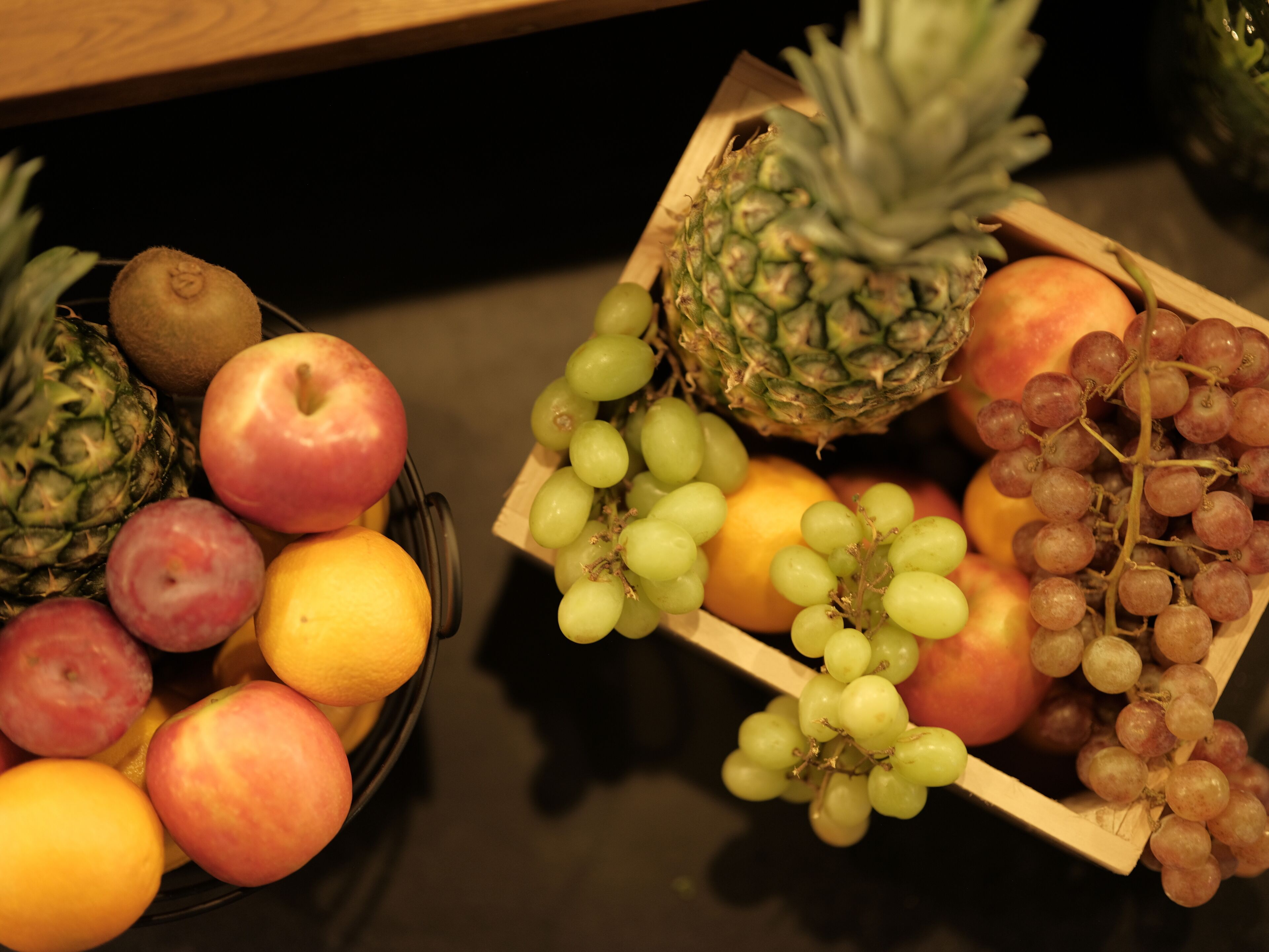 Duas cestas de madeira com frutas sobre uma mesa.