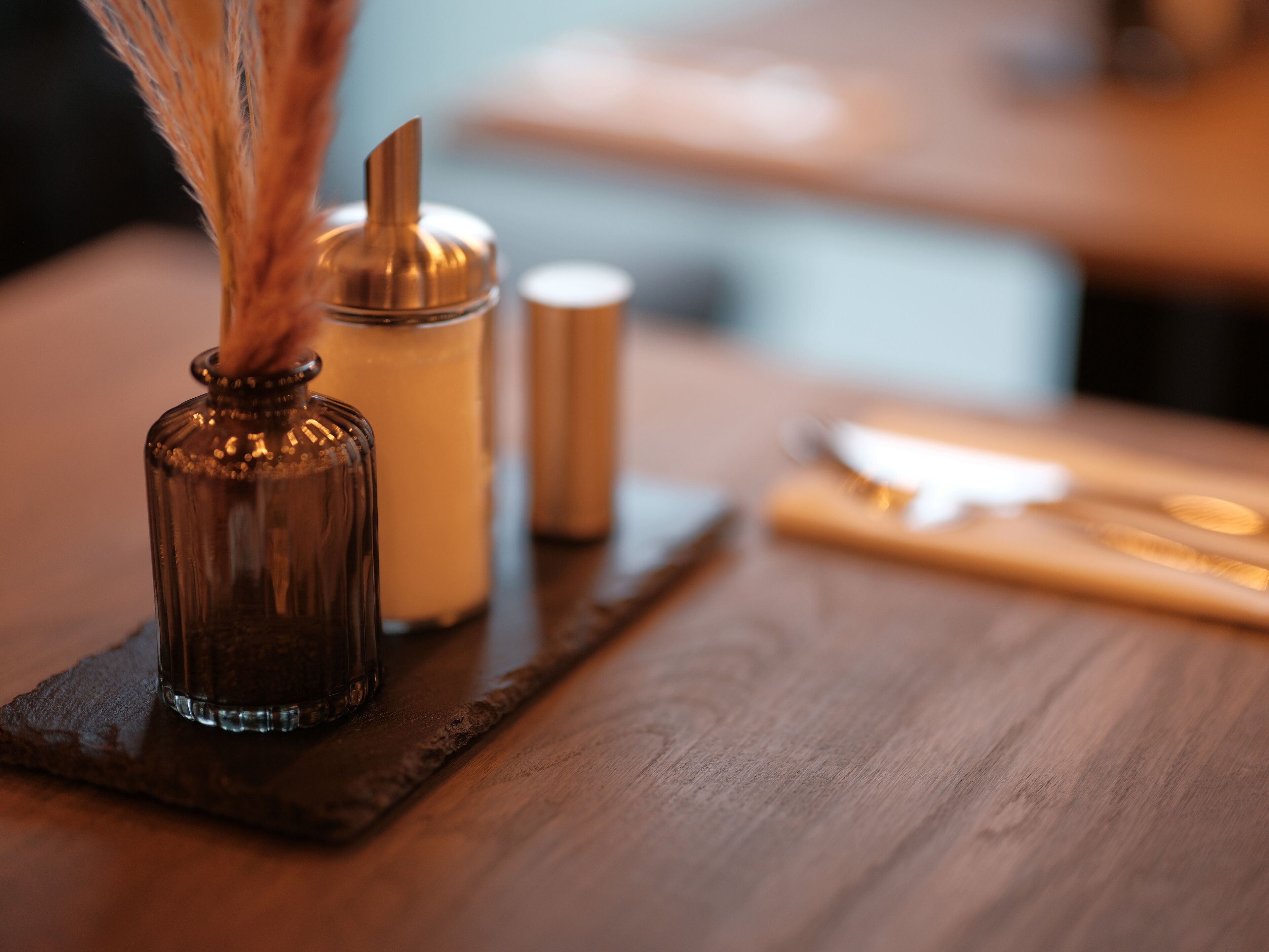 Una mesa de madera con una botella de vidrio, una vela y un salero.