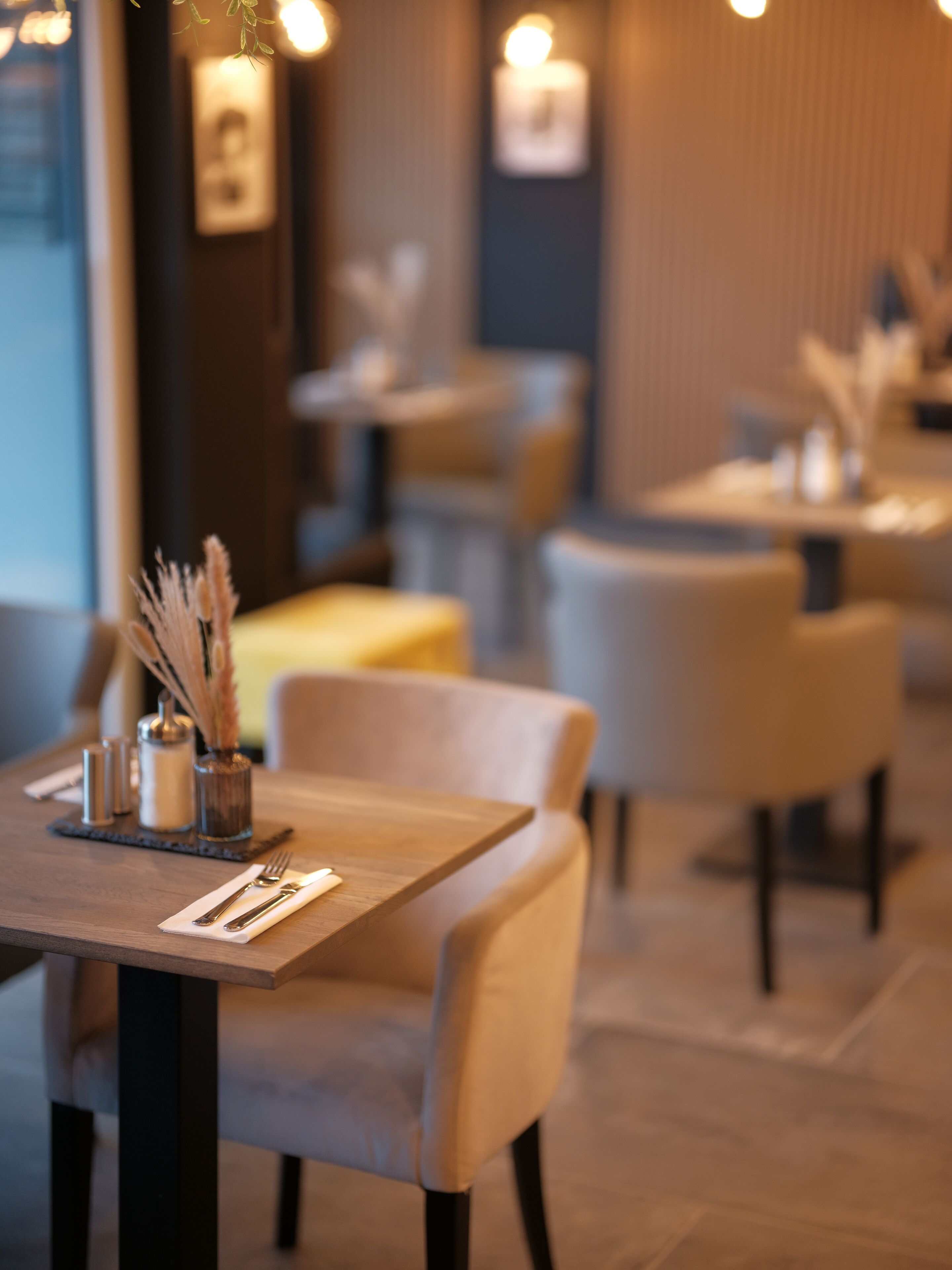 A restaurant interior with tables set for dining, chairs, and a decorative centerpiece on the table.