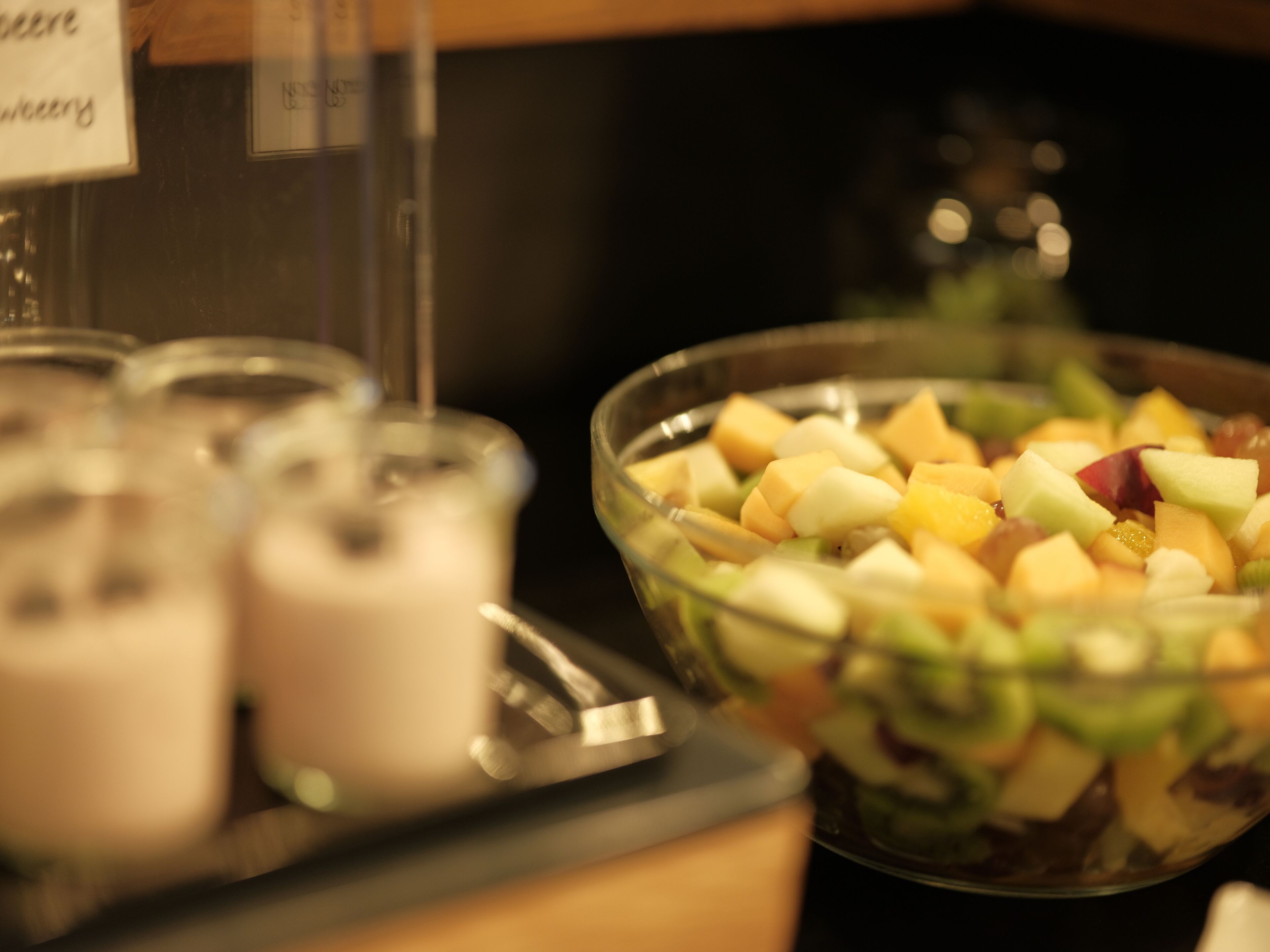 A bowl of fruit salad with a variety of fruits and a glass of a creamy beverage.