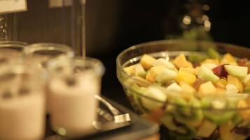 A bowl of fruit salad with a variety of fruits and a glass of a creamy beverage.