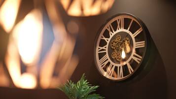 Un reloj de pared con números romanos y una planta decorativa debajo.