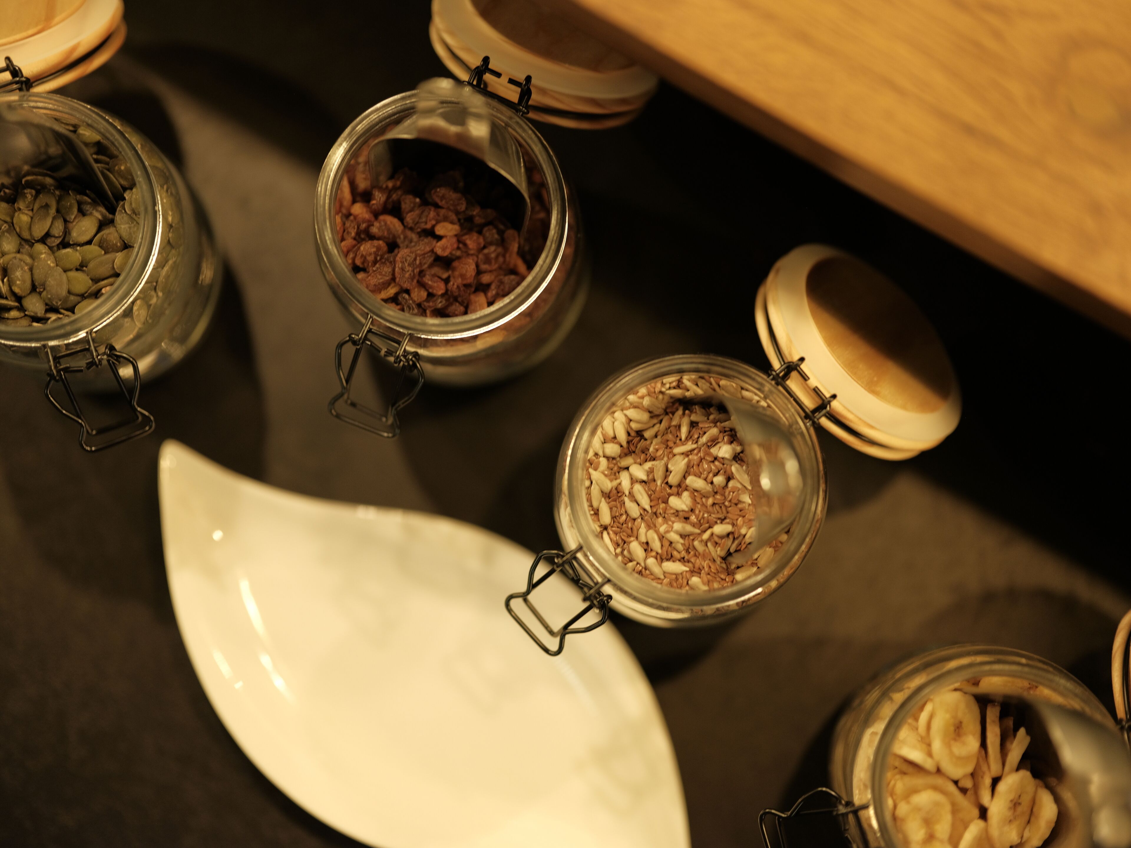 Diverse glazen potten met metalen deksels gevuld met verschillende soorten voeding, gerangschikt op een tafel.