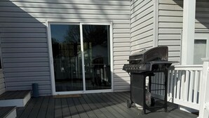 Una terraza con una parrilla y una puerta corrediza de vidrio que da a un patio cubierto.