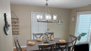 Un comedor con candelabro, sillas de madera y una mesa preparada para cuatro comensales.