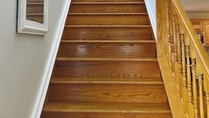 Una escalera de madera con paredes blancas y un cuadro enmarcado en la pared.