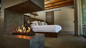 A modern bedroom with a bed, a fireplace, and a large window. - Fishers House Hotel Avándaro (Valle de Bravo)