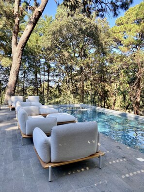 Una piscina al aire libre, sombrillas, sillones reclinables de piscina
