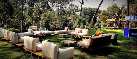 An outdoor seating area with multiple sofas and chairs, a fire pit, and a wooden table.