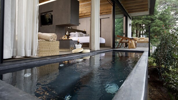 Quarto moderno com uma cama grande, televisão e vista para uma piscina.