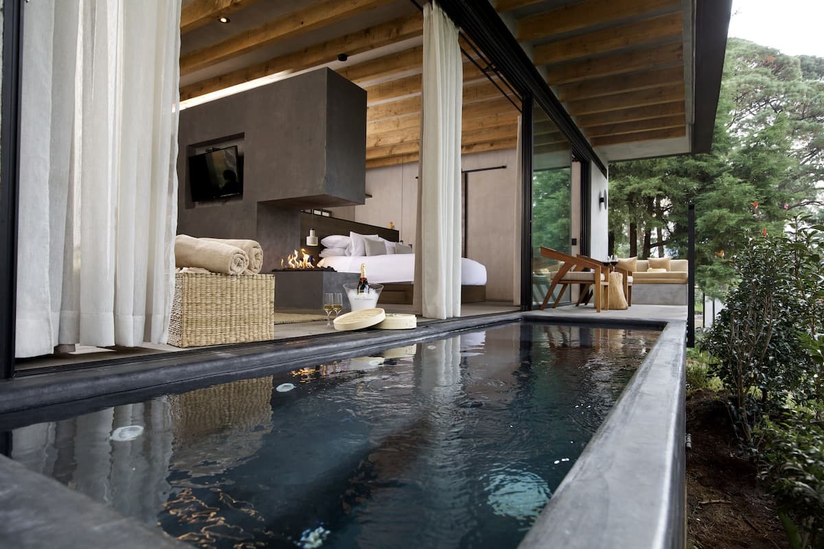 Ein modernes Schlafzimmer mit einem großen Bett, einem Fernseher und Blick auf einen Pool.