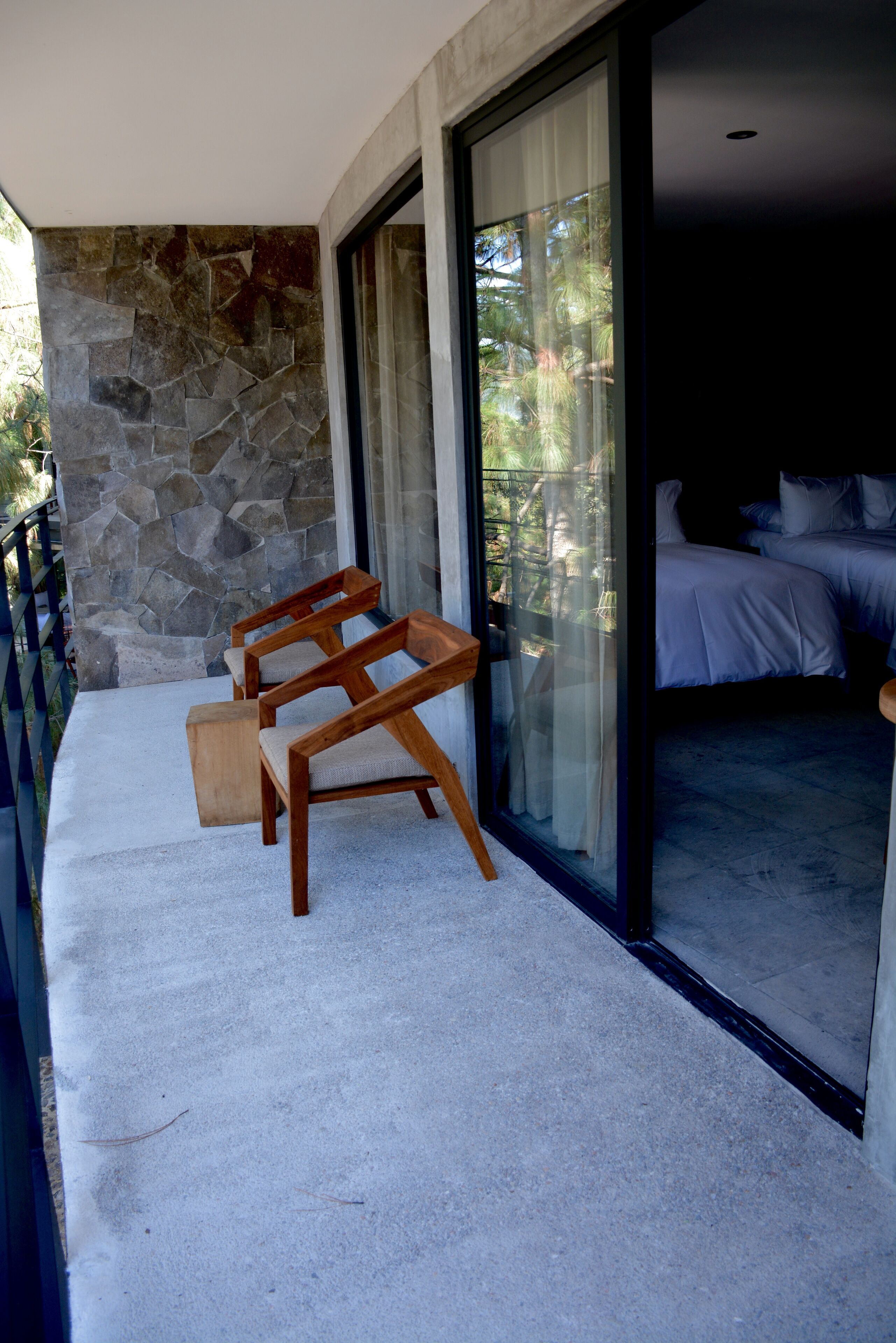A balcony with stone walls and a wooden chair.