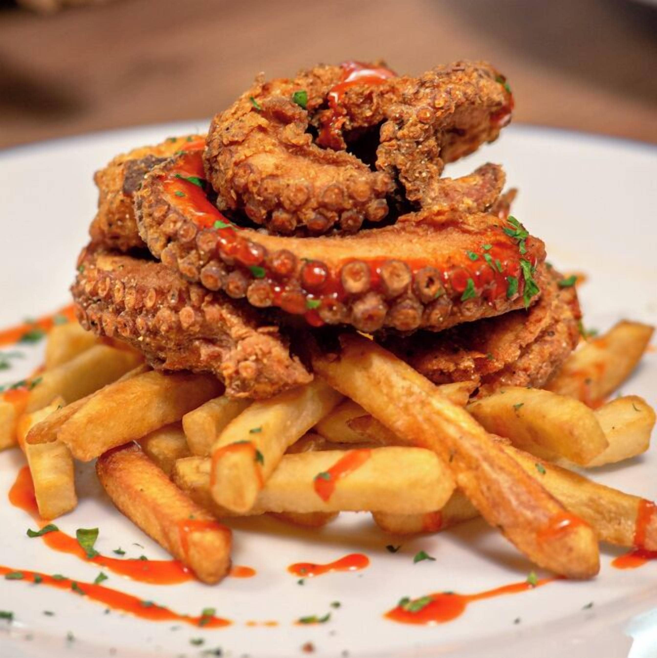 A plate of fried chicken and French fries with a red sauce.