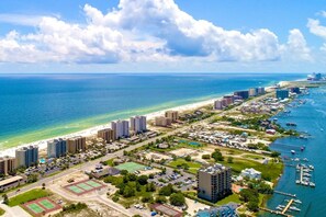 Vue aérienne d’une zone côtière avec des immeubles de grande hauteur, une plage et un port de plaisance.