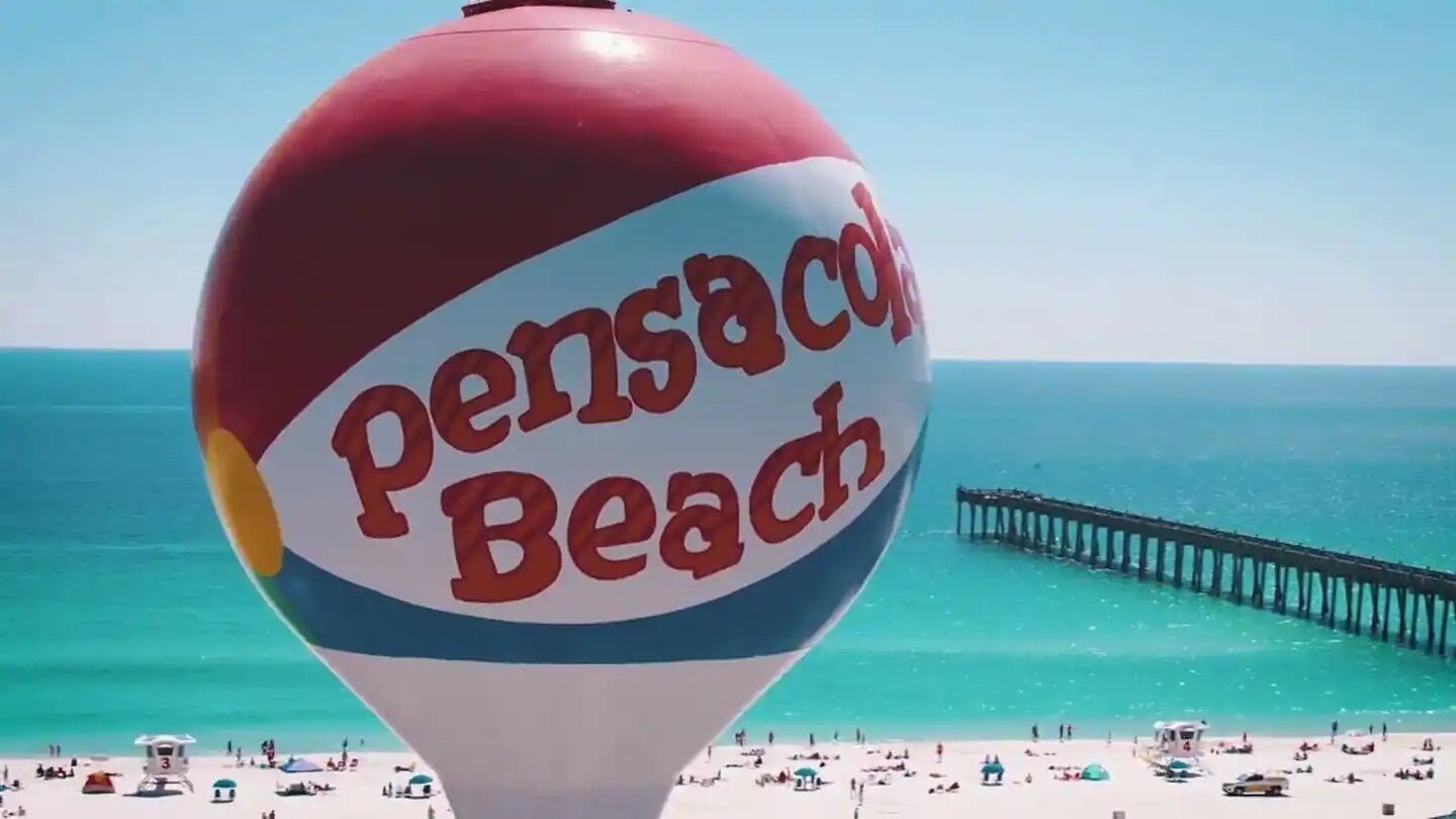 Rantakuva, jossa näkyy suuri punavalkoinen ilmapallo, jossa on teksti ”Pensacola Beach”.