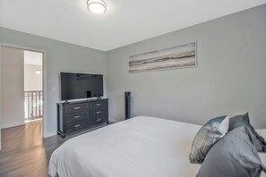 A bedroom with a bed, dresser, TV, and artwork on the wall. - Perfect Pensacola Getaway Near Beaches & Downtown! (Pensacola)