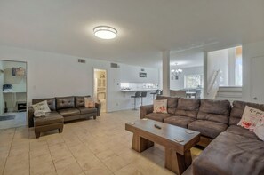 A spacious living area with two sofas, a coffee table, and a kitchen in the background.