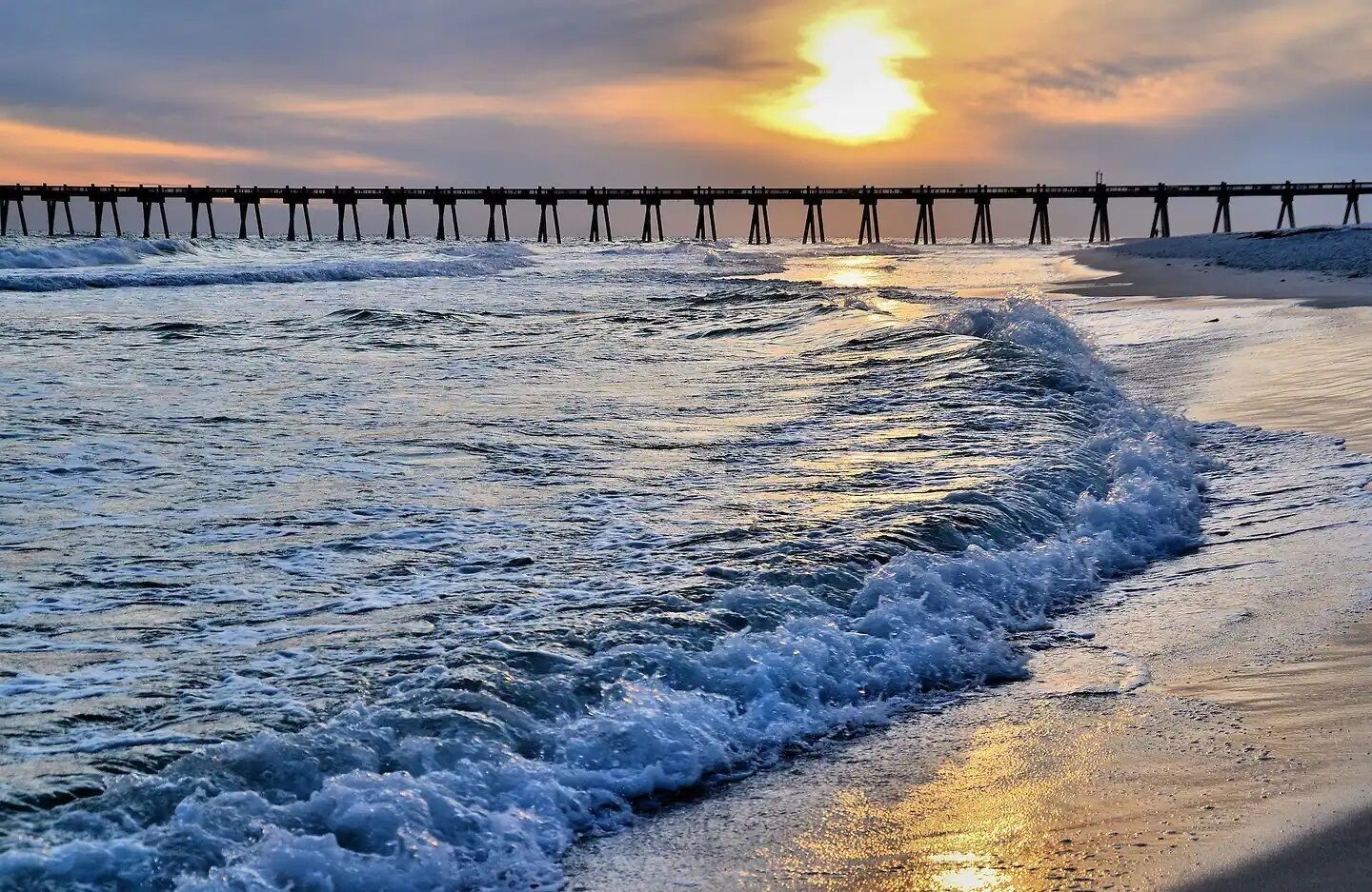 Une jetée qui s’avance dans l’océan, avec des vagues qui se brisent sur le rivage.