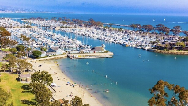 An aerial view of a marina with numerous boats docked, a sandy beach, and a pier extending into the water. - Exclusive Monarch Beach, Ritz Pointe Condo - 2 Bedroom, 2 Bath [STR23-0012] (Dana Point)