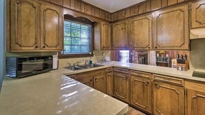 A kitchen with wooden cabinets, a built-in microwave, a sink, and a window with blinds. - Peaceful Home, Colleges-Hospitals-Shops Close, Corporate Bookings Welcome  (Jackson)