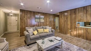 A living room with a grey sofa, wooden panel walls, a white coffee table, and a door leading to another room. - Peaceful Home, Colleges-Hospitals-Shops Close, Corporate Bookings Welcome  (Jackson)
