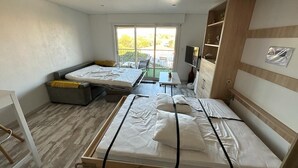 Ett modernt rum med två sängar, ett litet bord, en TV och en balkong med utsikt.