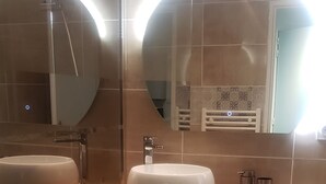 Ett badrum med två handfat, en spegel, en dusch och en tvättmaskin.