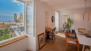 A dining area with a view of a historic building, a dining table, chairs, and a potted plant. - Le Saint-Jean (Bastia)