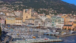 A coastal town with a marina filled with boats, historic buildings, and a prominent church. - Le Saint-Jean (Bastia)