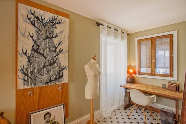 A room with a wooden desk, a mannequin, a framed picture, and a large abstract painting on the wall. - Le Saint-Jean (Bastia)