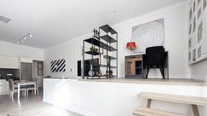Cozinha moderna com uma ilha central, área de jantar com mesa e cadeiras, e uma cadeira preta perto da ilha.
