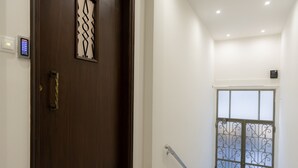 A wooden door with a decorative glass panel, a metal handrail, and a window with a metal grid design. - Plaka's Privileged Accommodation (Athens)