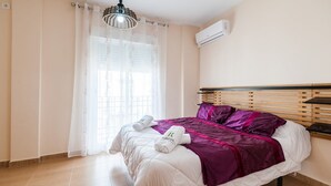 A bedroom with a bed, a window with sheer curtains, an air conditioning unit, and a wooden headboard. - Alojamiento Rural Villa Calatrava Santiago de Calatrava by Ruralidays (Jaén)
