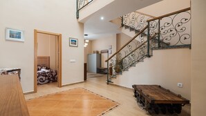 A spacious hallway with a wooden bench, a staircase with ornate metal railings, and a bed in the background. - Alojamiento Rural Villa Calatrava Santiago de Calatrava by Ruralidays (Jaén)