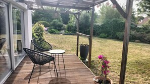 A covered patio with a table and chairs, a potted plant, and a view of a grassy yard. - Quiet little haven 5 kms from the port of La Rochelle  (Dompierre-sur-Mer)