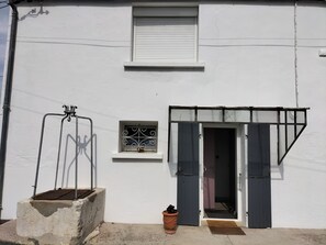 A white building with a closed shuttered window, a small window with decorative iron bars, and a door with a black frame. - Quiet little haven 5 kms from the port of La Rochelle  (Dompierre-sur-Mer)