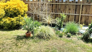 A fenced backyard with various plants and a small tree. - Quiet little haven 5 kms from the port of La Rochelle  (Dompierre-sur-Mer)