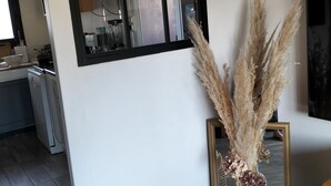 A modern kitchen with a large window, a dining area with a mirror, and a decorative vase with pampas grass. - Quiet little haven 5 kms from the port of La Rochelle  (Dompierre-sur-Mer)