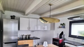 A modern kitchen with a wooden dining table, white cabinets, and a stainless steel refrigerator. - Quiet little haven 5 kms from the port of La Rochelle  (Dompierre-sur-Mer)