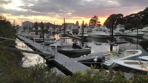 A marina with boats docked, a dock, and a sunset in the background. - Nestled in Cataumet, One of the Cape’s Hidden Gems (Bourne)