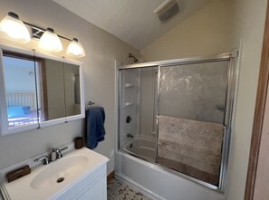 Een badkamer met een witte wastafel, een spiegel en een douchecabine van glas.